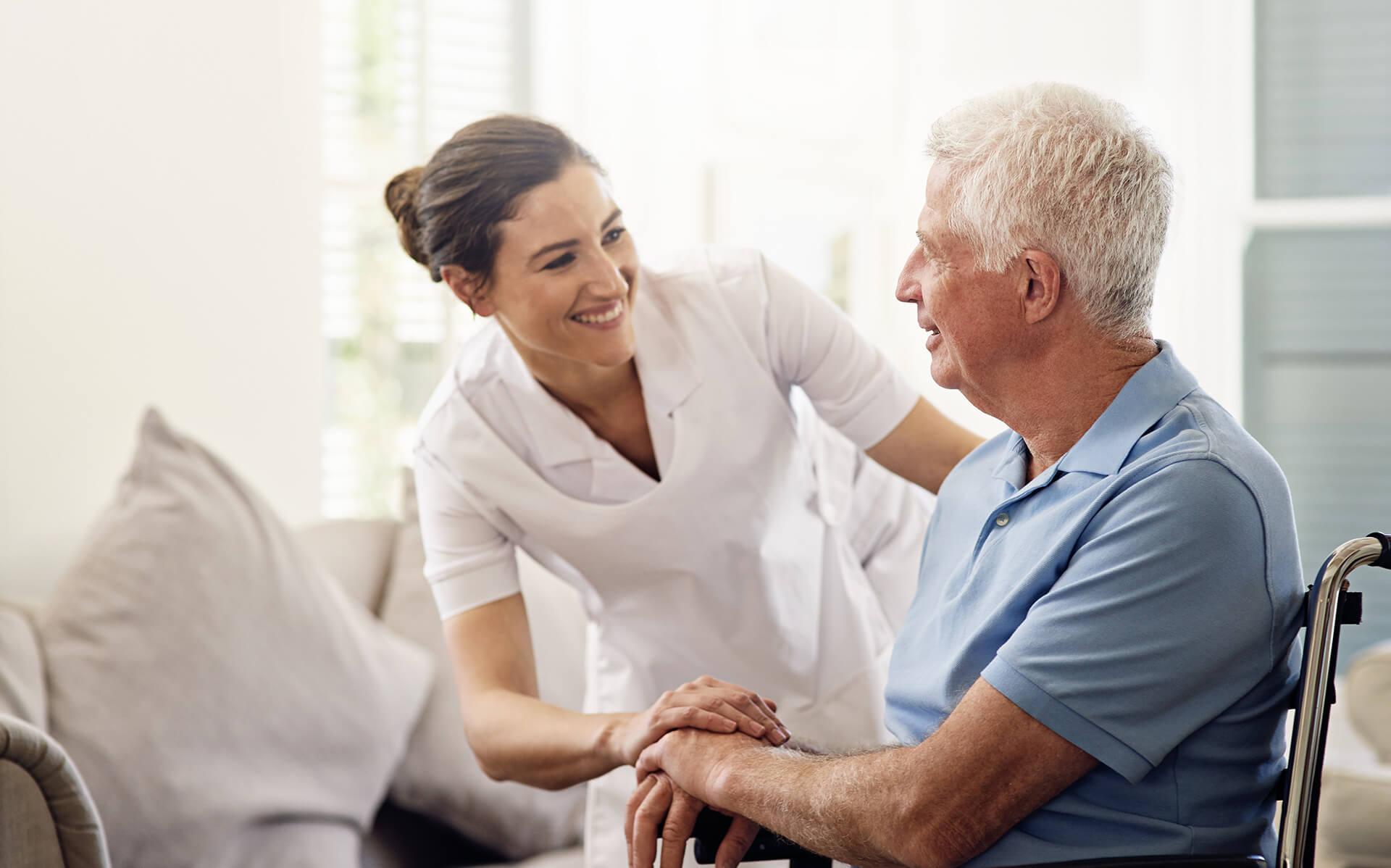 nurse attending to an elderly man in a wheelchair